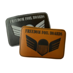 Custom Freedom Foil Boards leather patches featuring premium black and tan faux leather, laser-engraved branding, winged logo, and rectangular design for hats, apparel, and outdoor gear